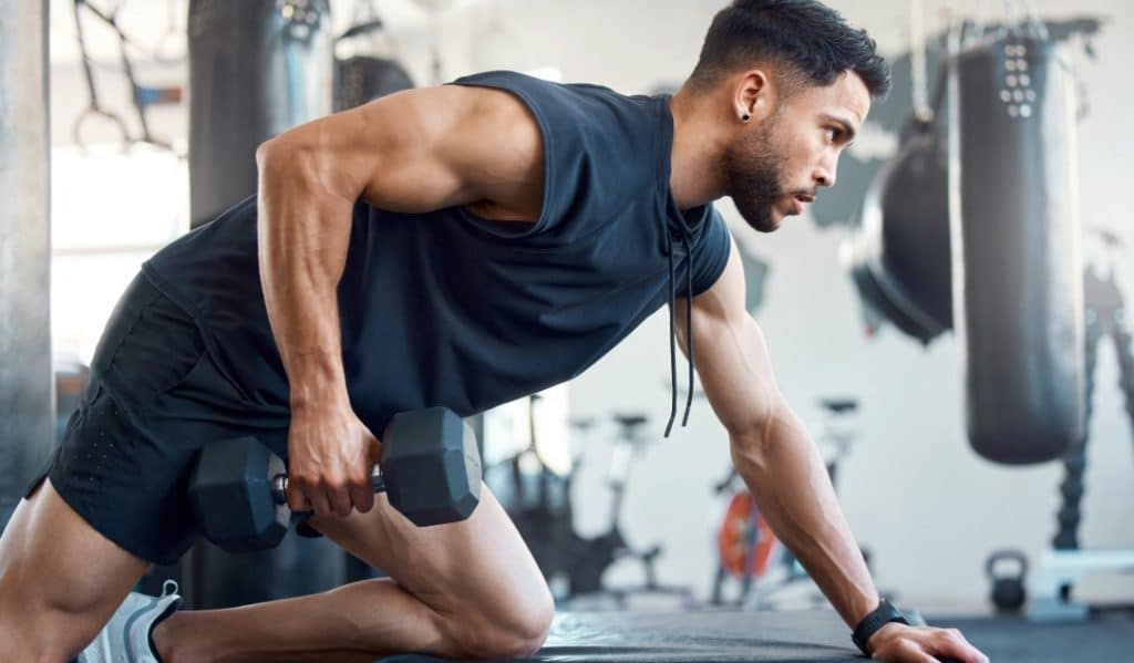 A man lifts weights at the gym after using Emsculpt Neo muscle toning