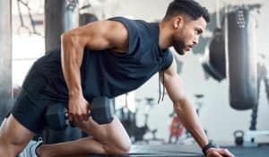 A man lifts weights at the gym after using Emsculpt Neo muscle toning