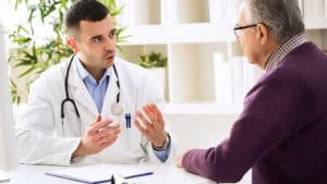 A doctor in a lab coat discusses personal injury recovery with a patient