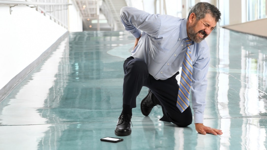 A man holds his back in pain after experiencing a fall at the office