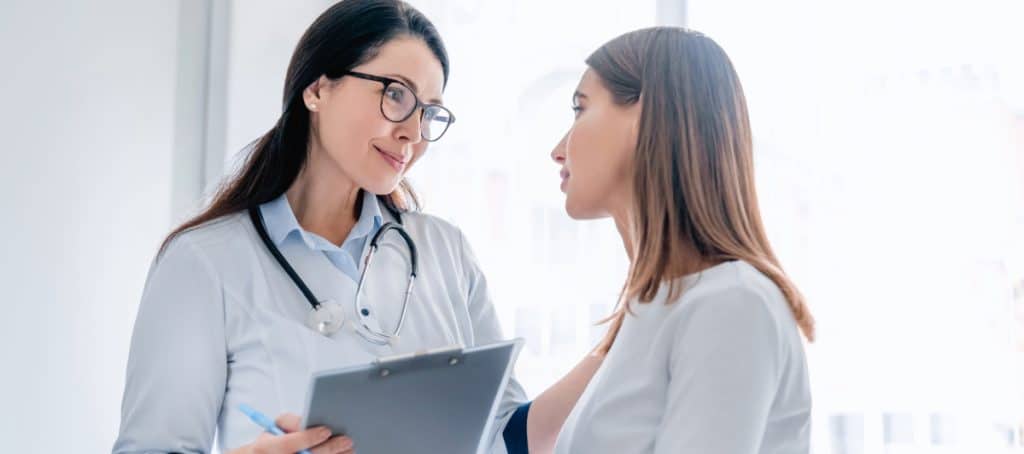 A doctor puts her hand on a patient's shoulder as she discusses tips for diabetic foot care