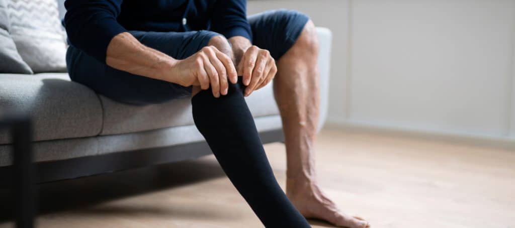 A man pulls up his compression socks as part of proper diabetic foot care