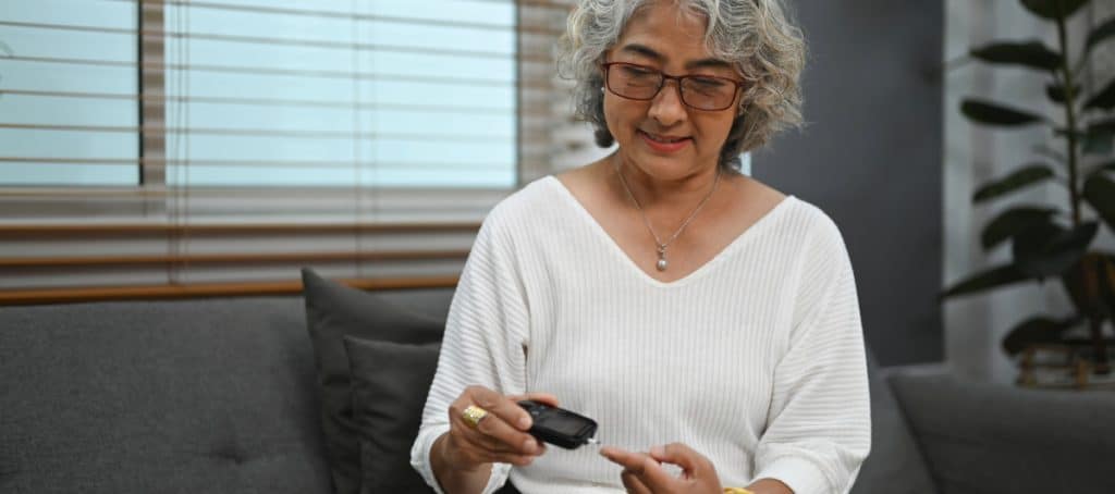 A woman uses a device to check her blood sugar levels due to diabetic neuropathy