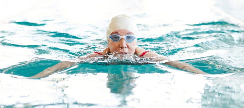 A person swims with googles and a swim cap on to ease symptoms of diabetic neuropathy