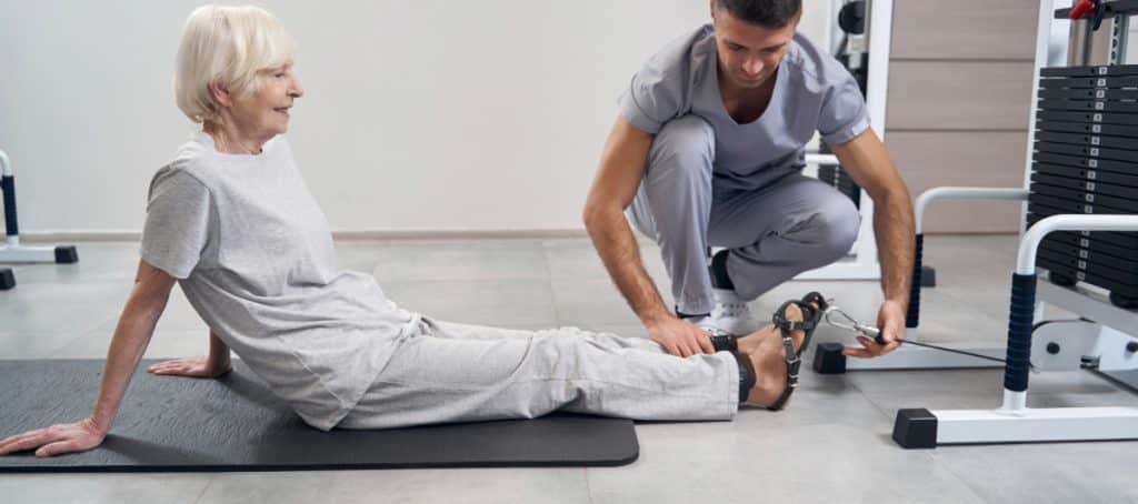 A physical therapist helps an older woman exercise her foot as part of proper diabetic foot care