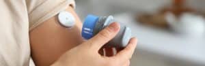 A person with diabetes checks their glucose levels with a CGM sensor