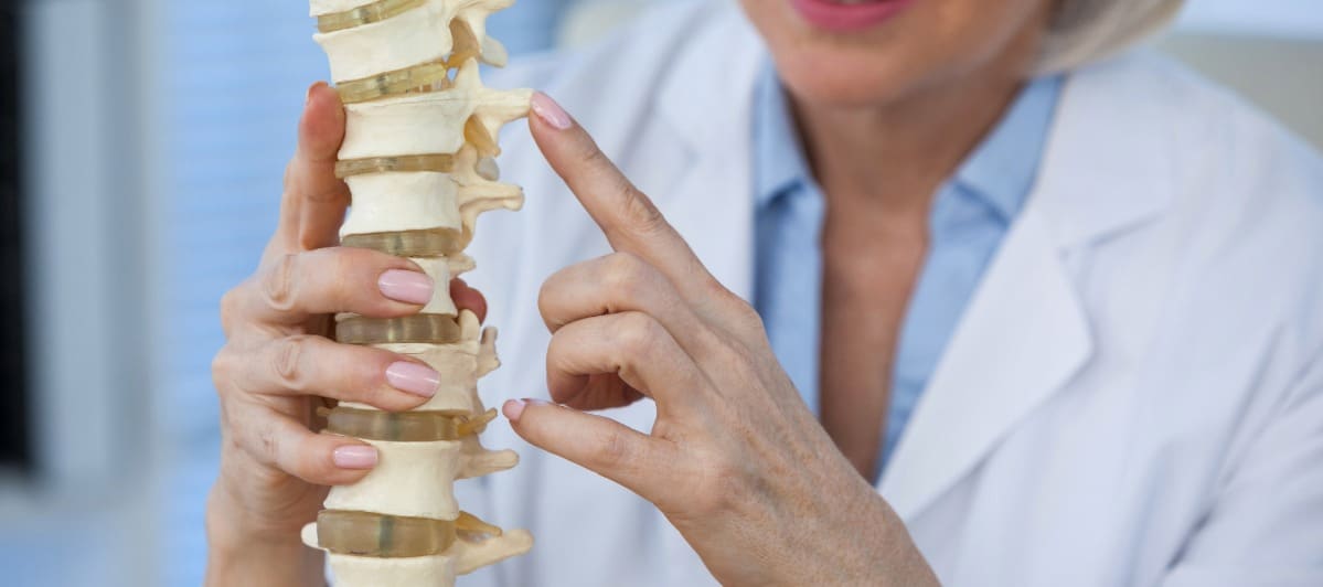 Types of Spine Surgery Explained-3-Spine A doctor points to a model of the spine as she explains the different types of spine surgery