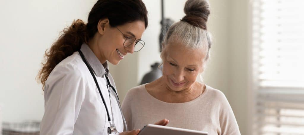A smiling doctor shows her patient a treatment plan for the stages of diabetic neuropathy