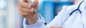 A doctor in a lab coat prepares a needle before an injection therapy session