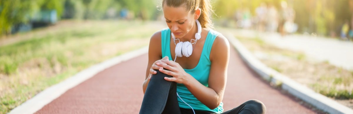 What Is Injection Therapy-5 A runner sits on the track and holds her knee due to injury before injection therapy