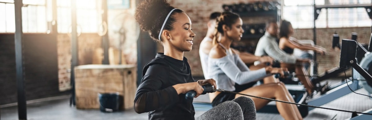 What Is an Epidural Injection-6-Gym A woman smiles as she exercises on a rowing machine at the gym