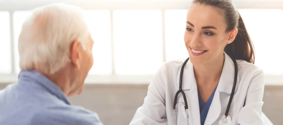 What Should I Know About Kyphoplasty-2-Doc A doctor in a lab coat smiles as she discusses kyphoplasty with a patient
