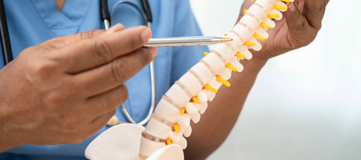 What Should I Know About Kyphoplasty-4-Spine A doctor in scrubs uses a pencil to point at a model of the spine