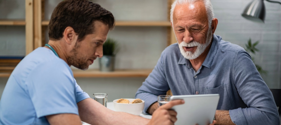 What Should I Know About Kyphoplasty-5-Patient An older patient smiles as he looks at the results after kyphoplasty with a doctor