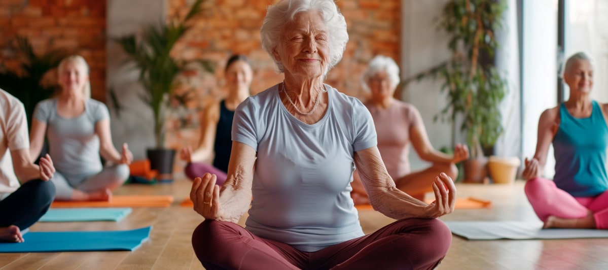 What Should I Know About Kyphoplasty-6-Yoga An older woman smiles as she sits cross-legged with her eyes closed as she meditates