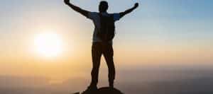 A person standing on a mountaintop with arms raised