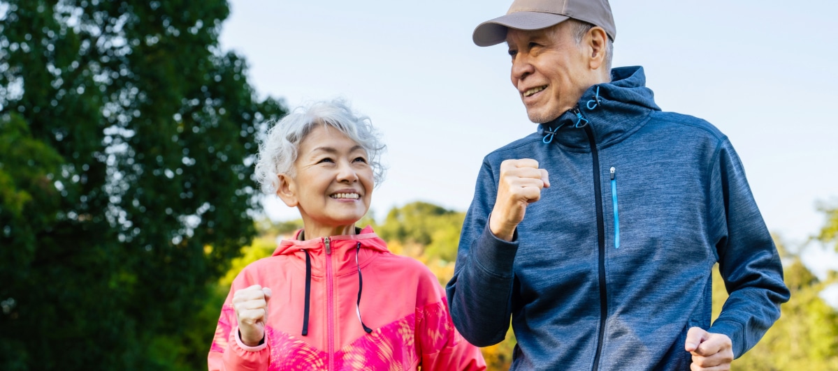 What You Need to Know About Surgical Decompression-5-Joggers An older couple smiles as they jog through a park after spinal decompression treatment