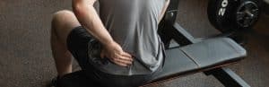 A person holds his back in pain while at the gym due to * lower back pain after surgery