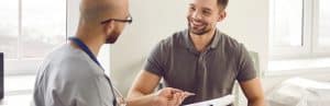 A patient smiles as his doctor tells him about glucose monitoring implants for diabetes management