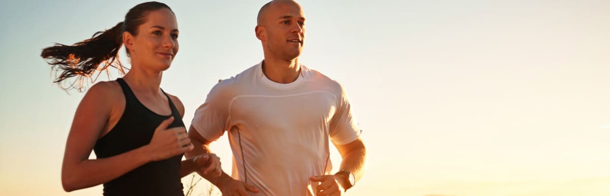 What to Expect When Getting a Glucose Monitoring Implant-5 A man and woman smile as they jog at sunset after receiving glucose monitoring implants