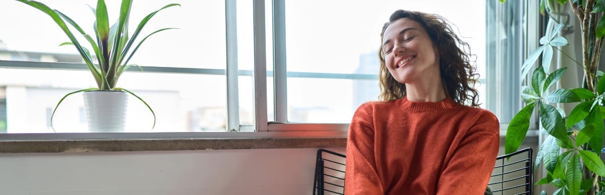 What to Expect When Getting a Glucose Monitoring Implant-6 A woman sits in a chair, closes her eyes, and smiles after making diabetes management easier with a glucose monitoring implant