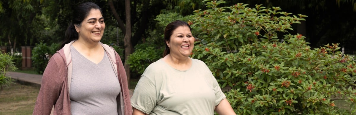 When to Eat to Optimize Health and Wellness-3-Walkers Two women smile as they walk through a park after alternative pain relief treatment