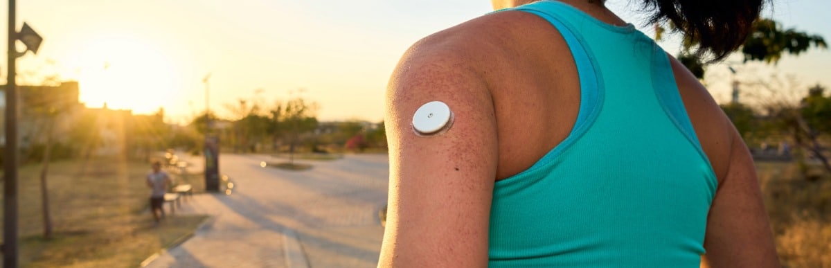 Why CGMs Are Changing Diabetes Care-5 A runner jogs through a park with a version of CGMs on her arm