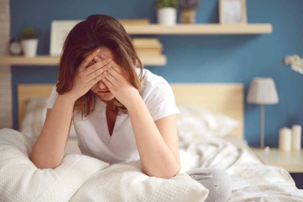 a women on her bed suffering from a headache