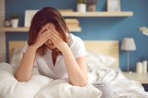 a women on her bed suffering from a headache