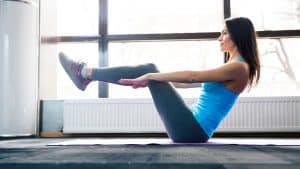 A women in a blue shirt and black pants practicing yoga